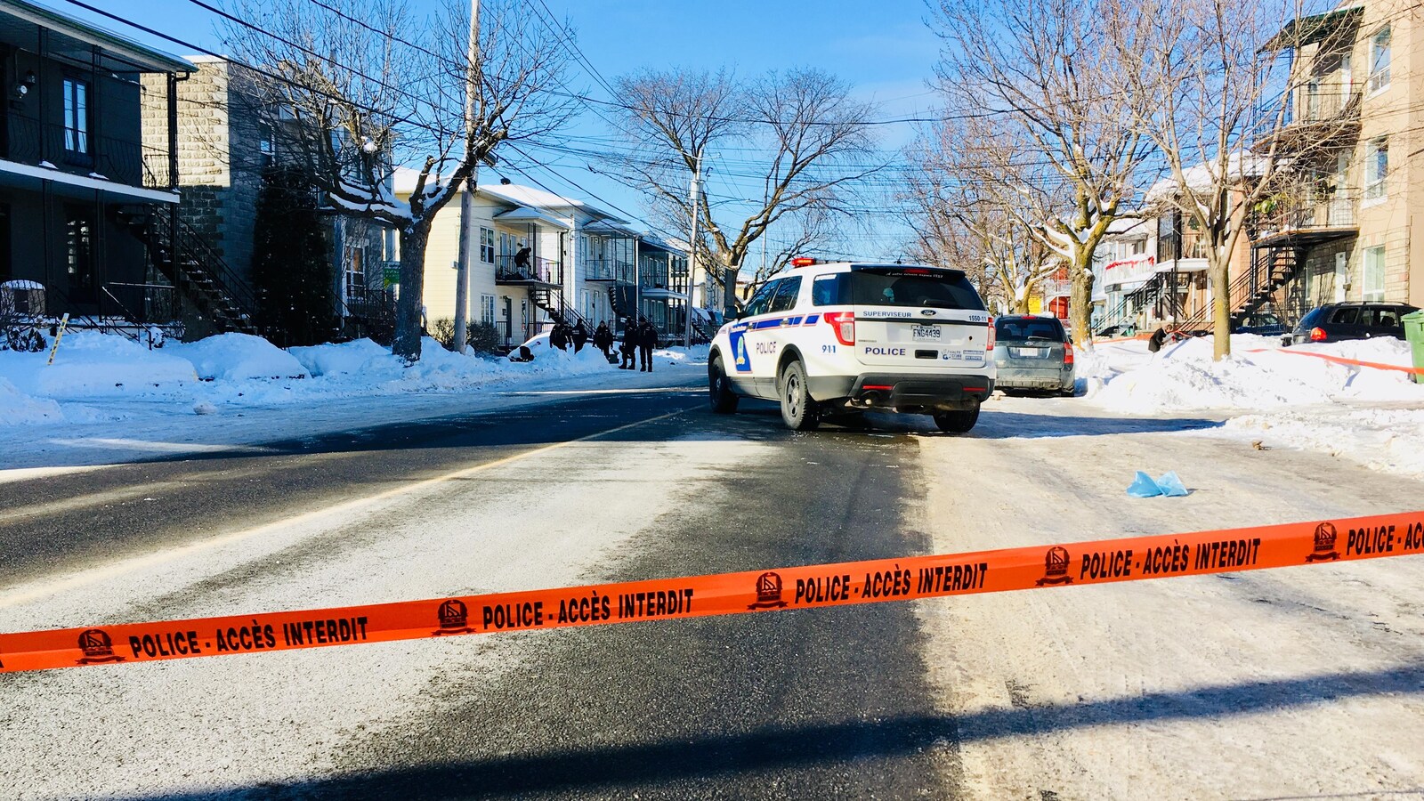 Un ruban policier empêche la circulation sur une rue résidentielle.