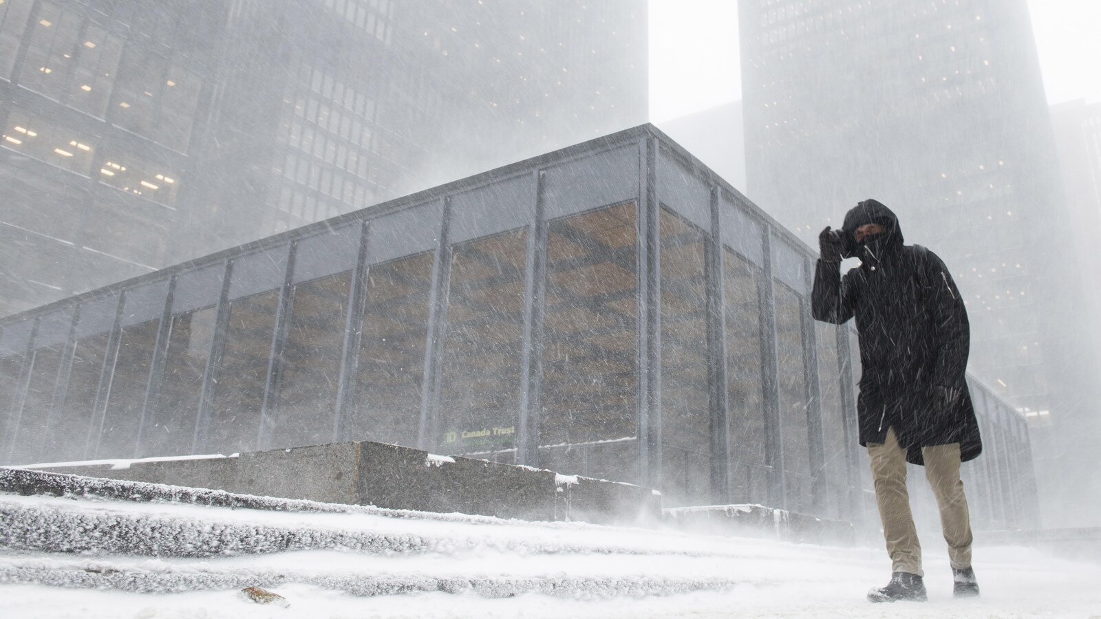 Un homme marche dans la tempête de neige à Toronto.