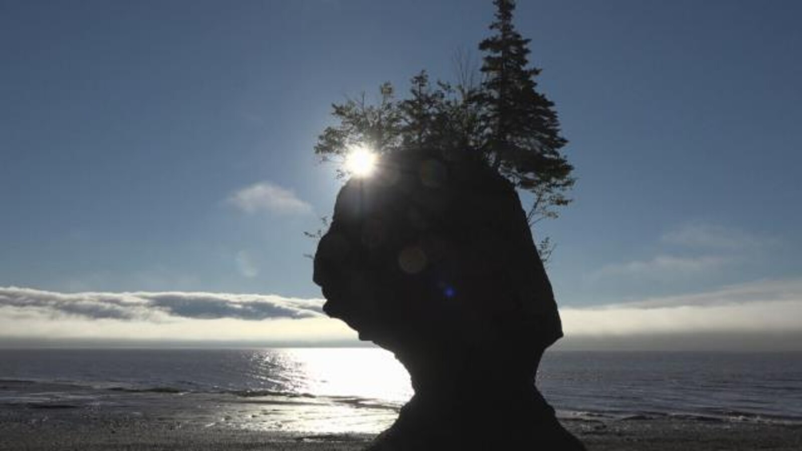 Le Soleil se couche derrière un rocher devant la baie de Fundy