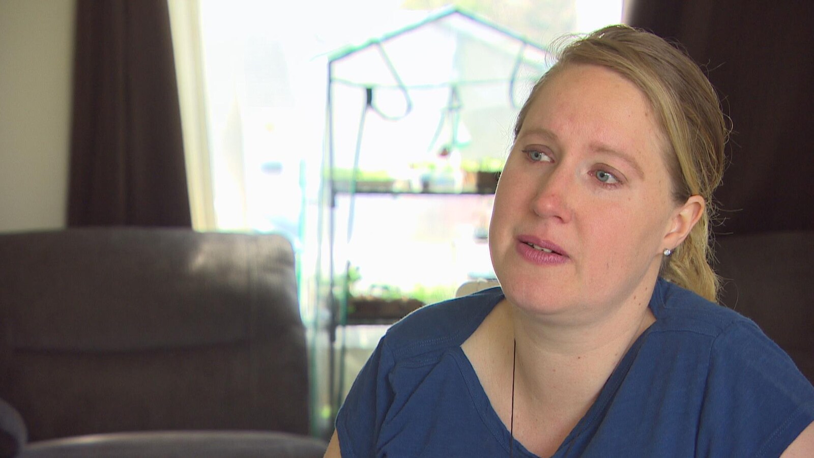 Une femme blonde, la tête penchée sur le côté, a les larmes aux yeux.