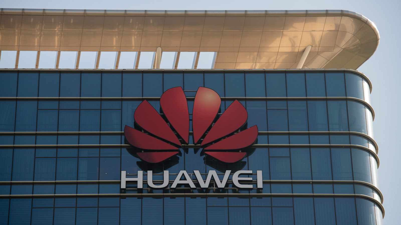 Gros plan sur le logo de Huawei sur la façade d'un gratte-ciel vitré.