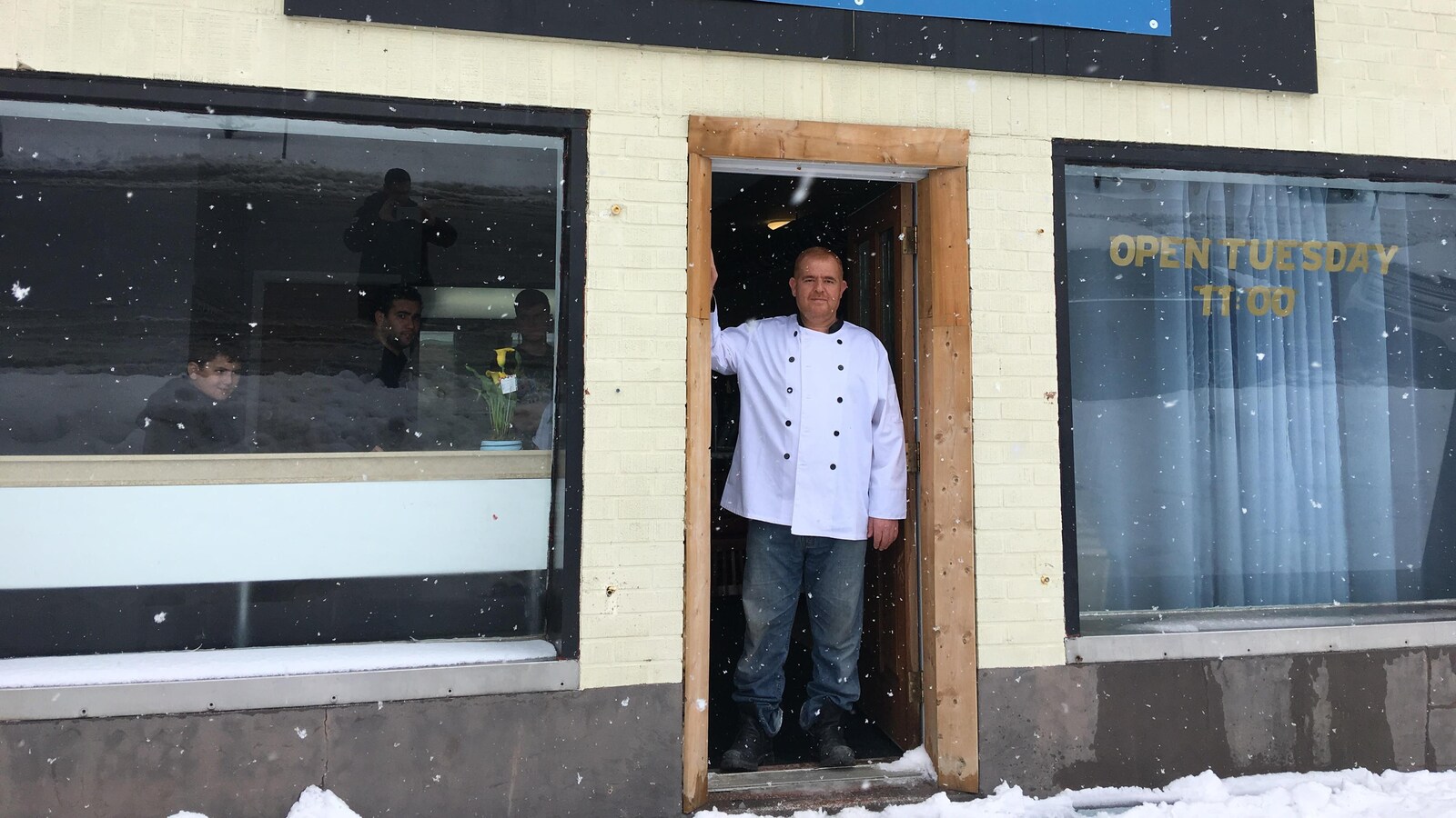 Un homme devant la façade d'un restaurant.