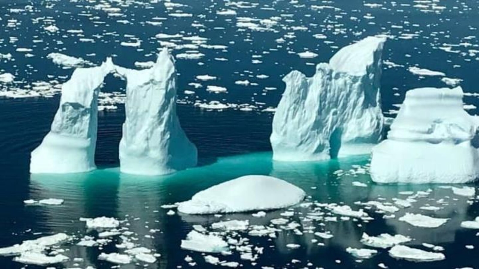Un iceberg à quatre pointes dans la mer près de White Bay, avec de l'eau turquoise qui l'encercle.