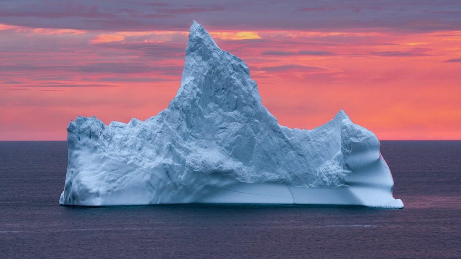 Un iceberg devant le soleil couchant.