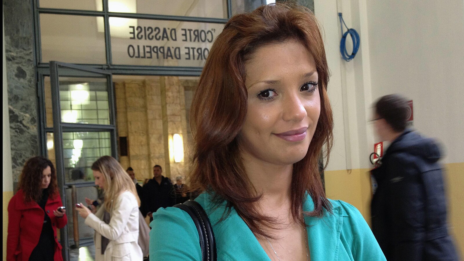 Une jeune femme sourit à la caméra à sa sortie d'un tribunal italien.