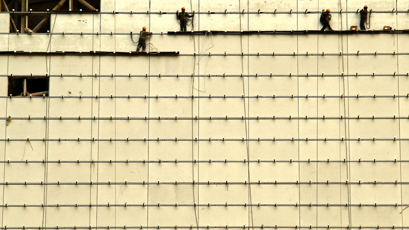 Des travailleurs sont debout sur des planches de bois à l'avant d'un bâtiment en construction dans le centre de Pékin, le 13 février 2012.