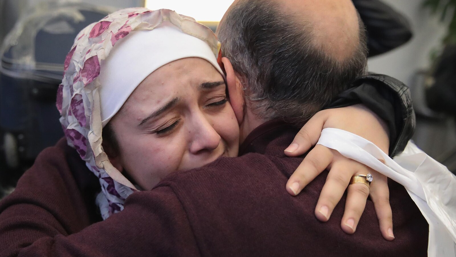 Une femme musulmane enlace son père dans un aéroport.