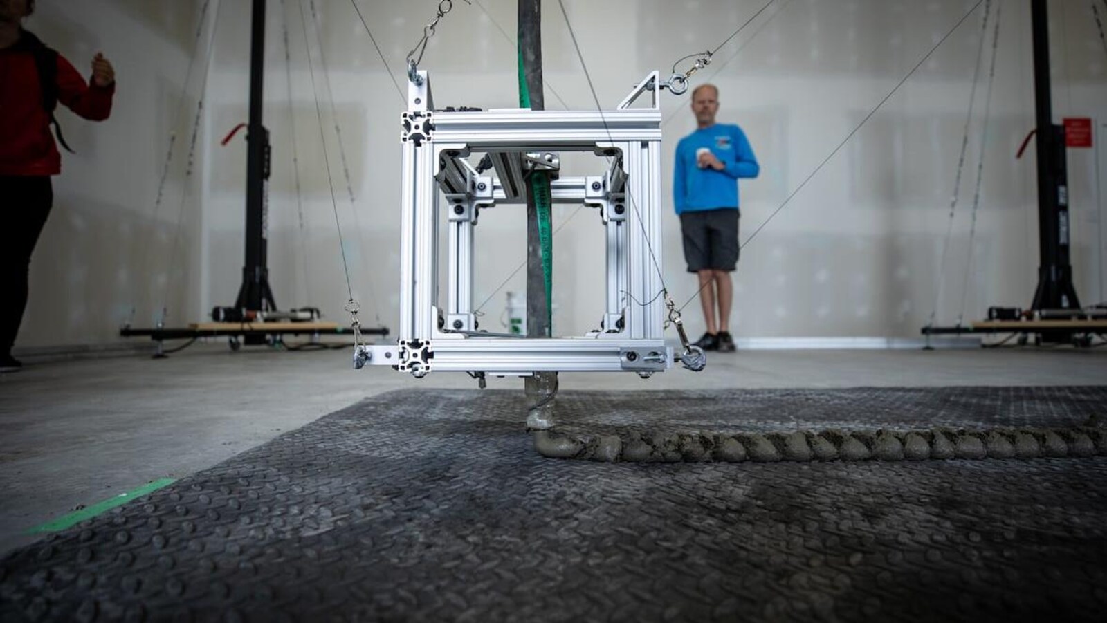 Une machine en forme de cube qui dépose du béton au sol.
