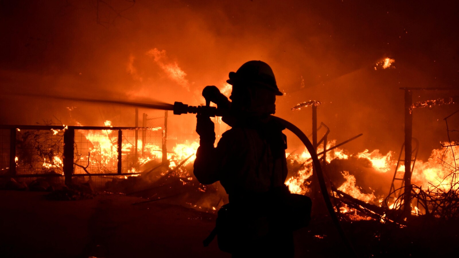 Un pompier lutte contre les flammes à l'aide d'un boyau d'incendie.