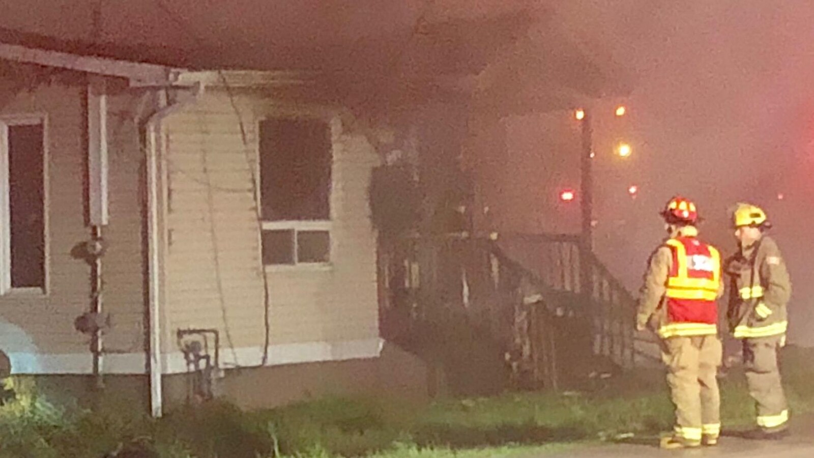 Deux pompiers devant une maison détruite.