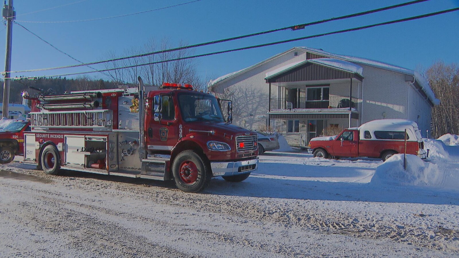 Camion de pompier devant un immeuble à logements en hiver.