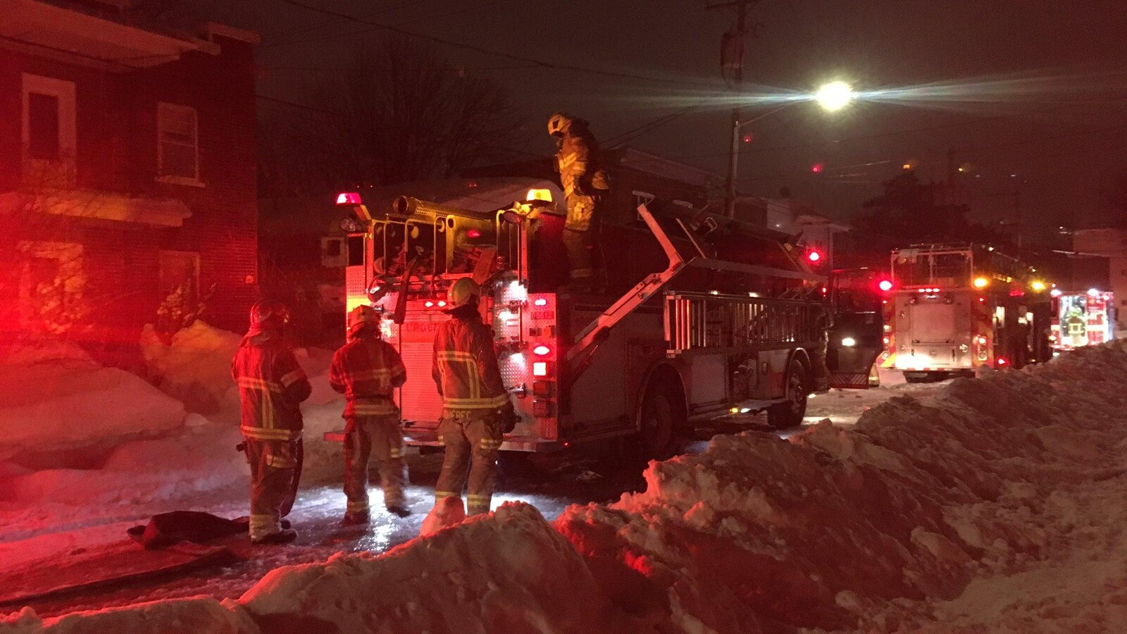 Trois pompiers s'affairent devant leur camion.