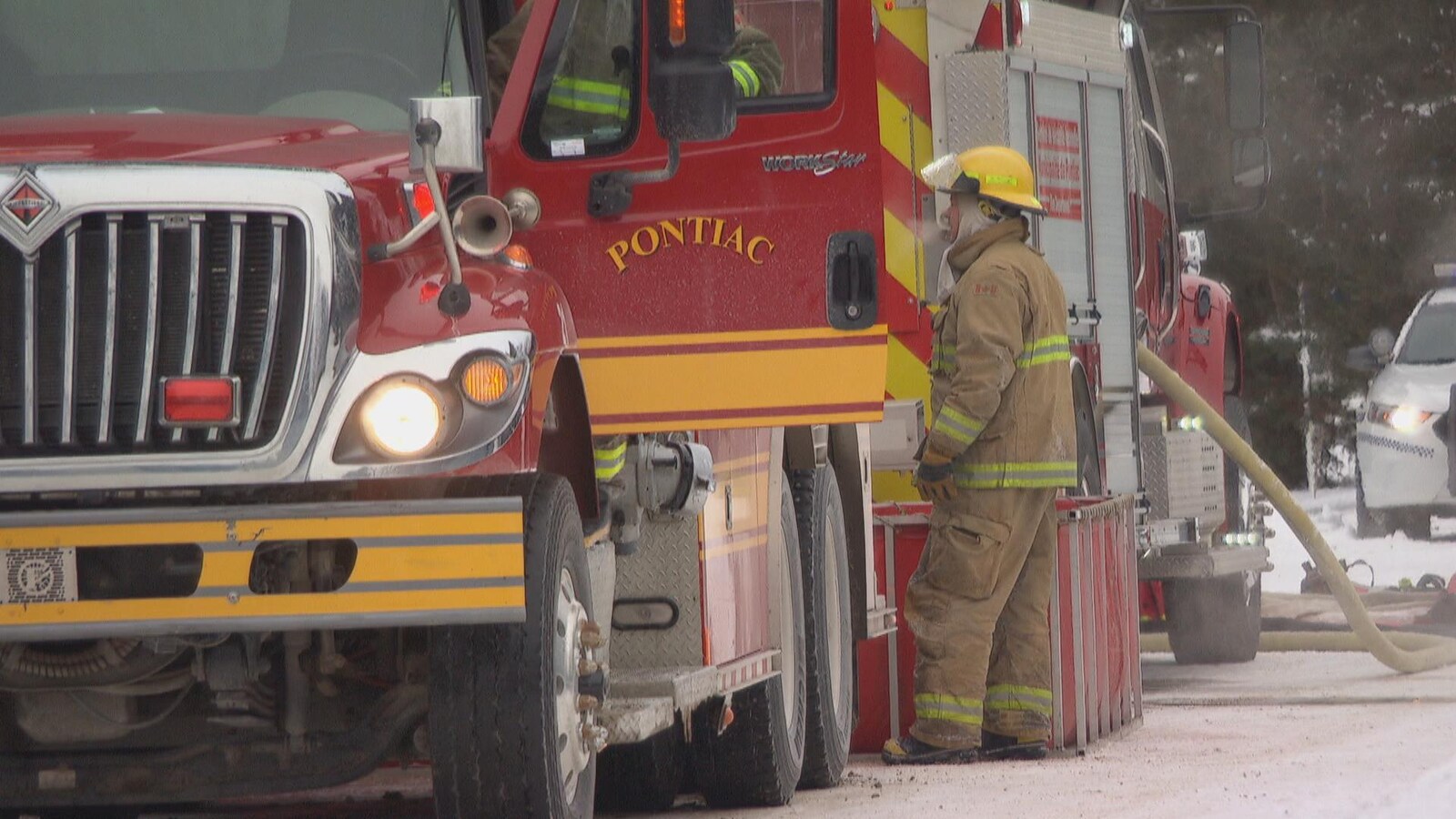 Un pompier devant un camion rouge sur lequel il est écrit Pontiac.