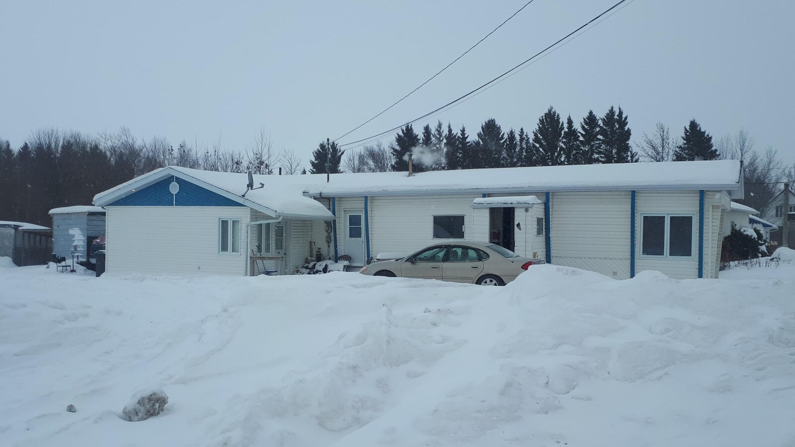 Une maison mobile devant laquelle est stationnée une voiture.