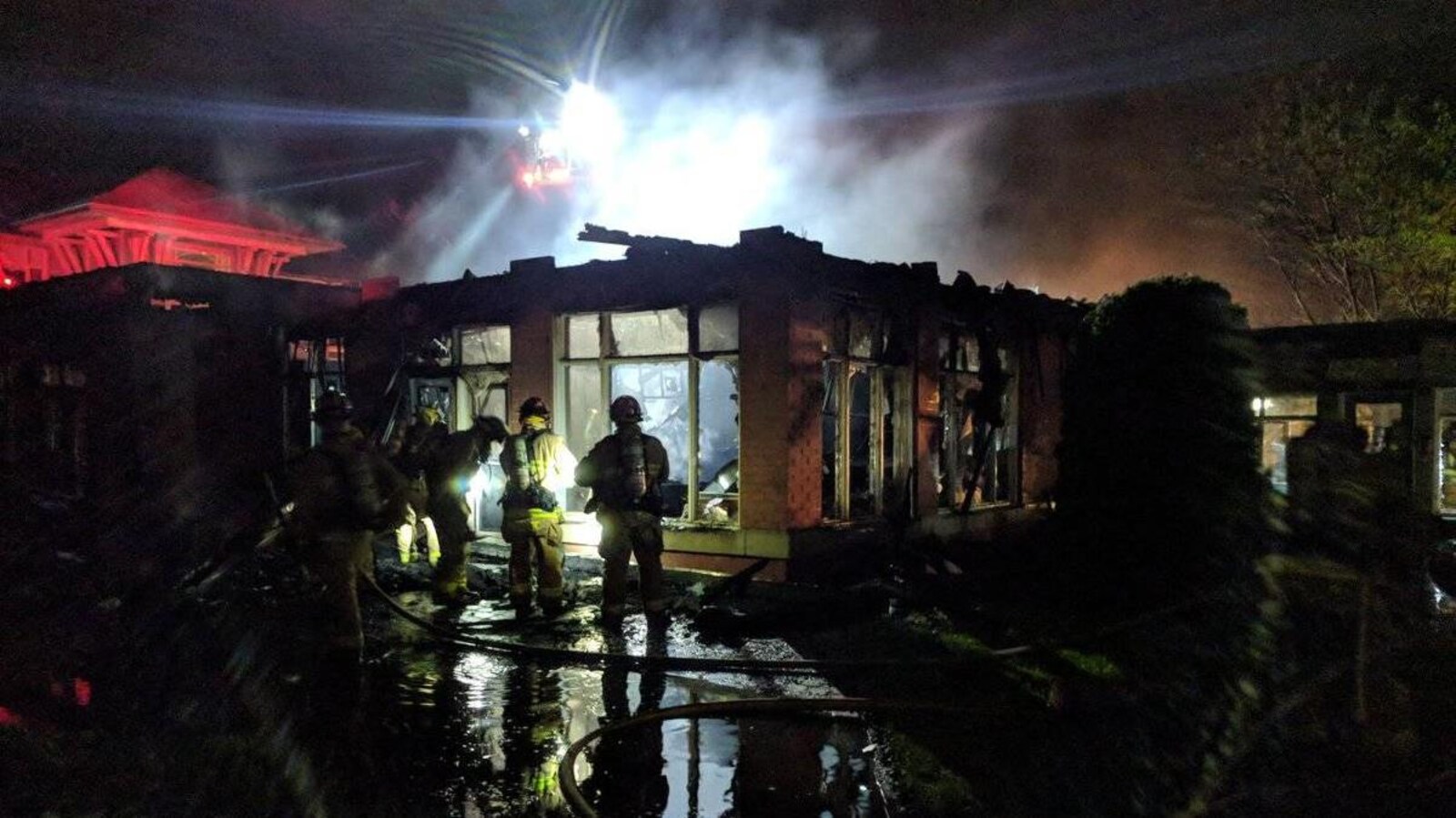 Des pompiers devant des logements détruits par les flammes.