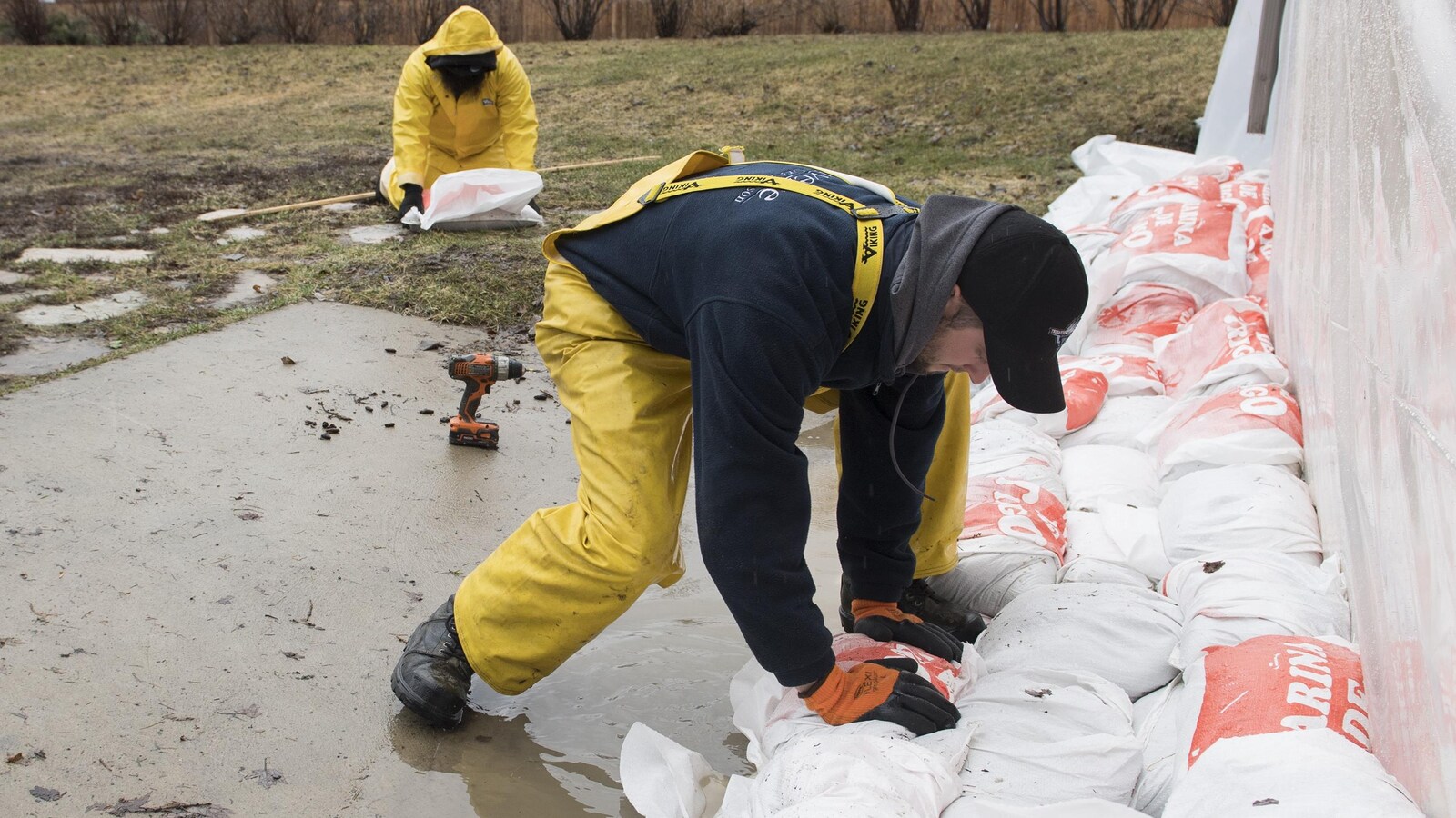 Un homme pose un sac de sable à côté de la fondation d'une maison dans la ville de Hudson, à l'ouest de Montréal, le vendredi 19 avril 2019.