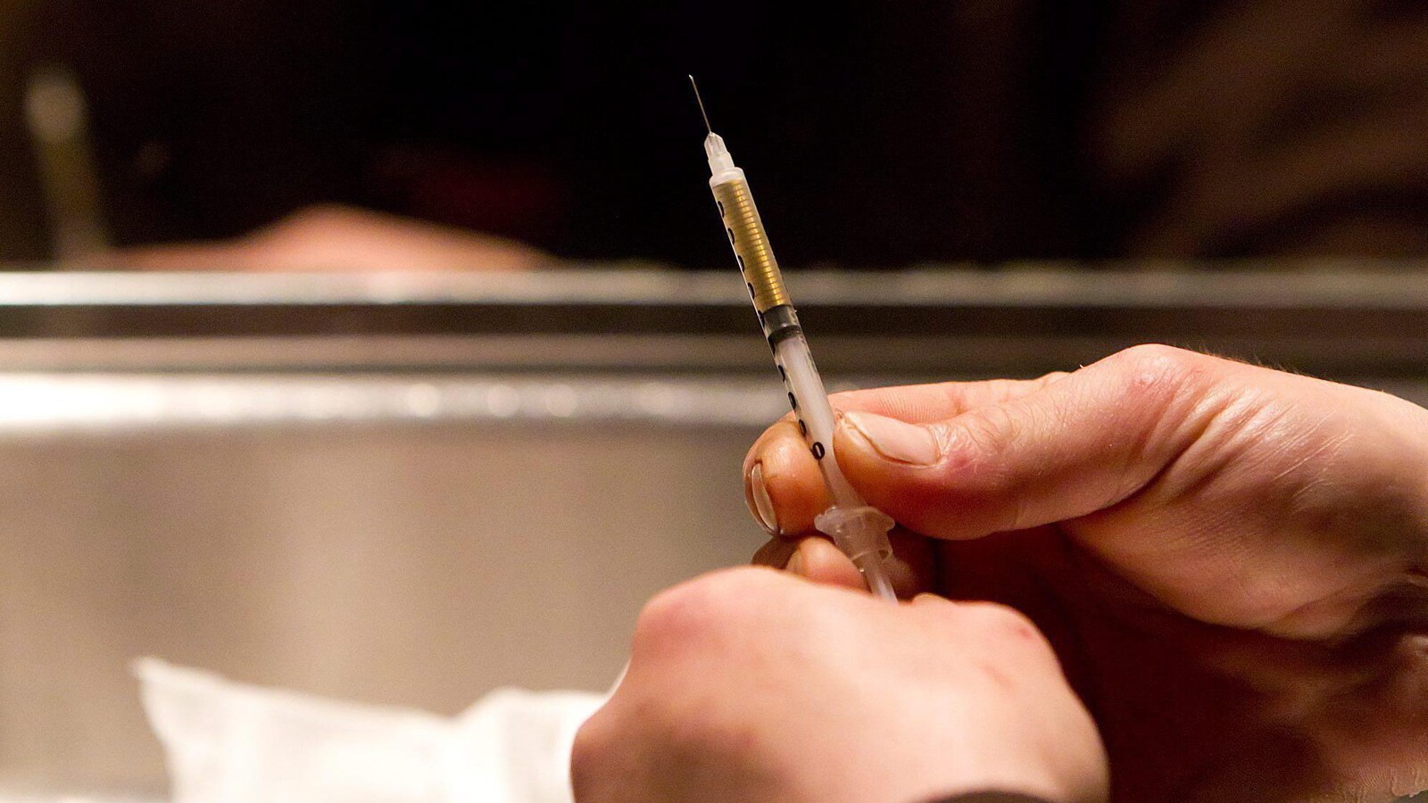 Un toxicomane se prépare à s'injecter de l'héroïne avec une seringue.