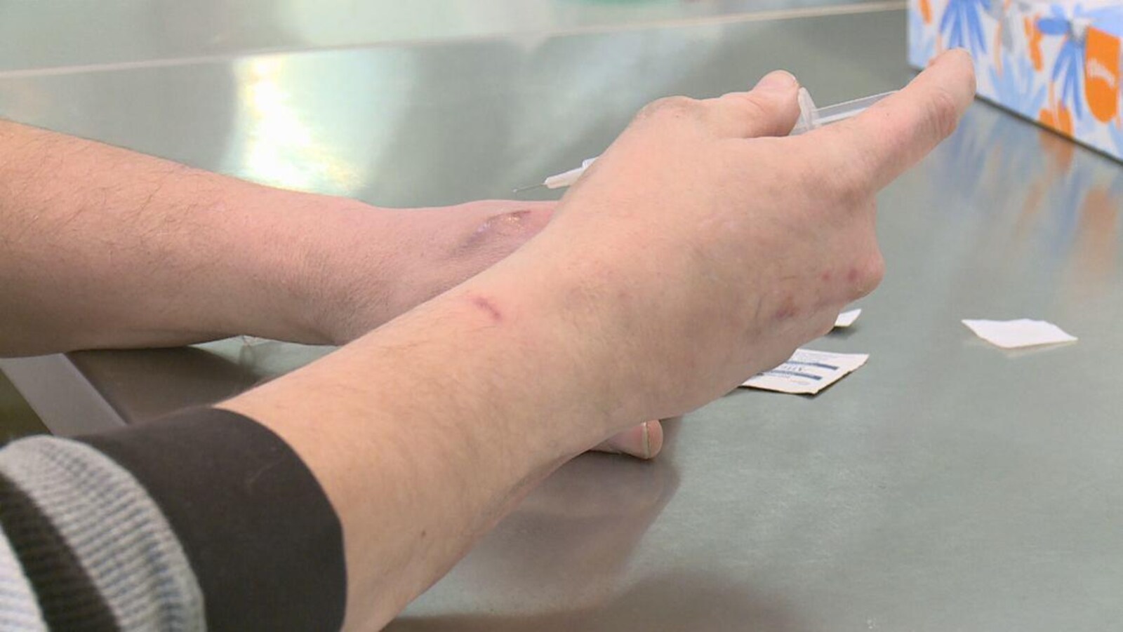 Gros plan sur des mains utilisant une seringues pour s'injecter de la drogue.