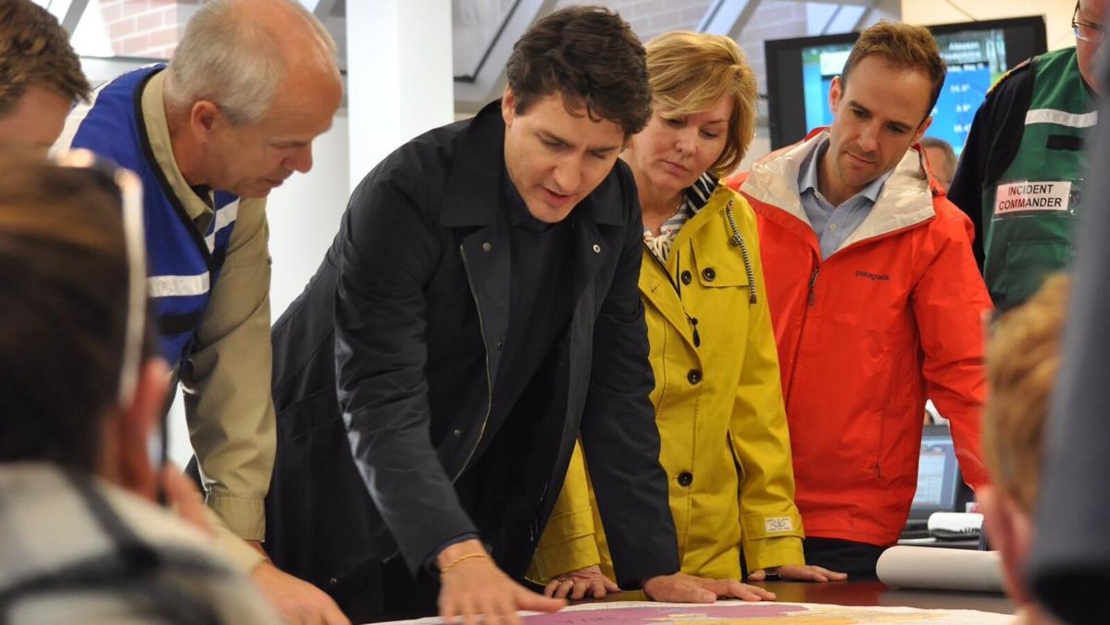 Le premier ministre du Canada, Justin Trudeau, et des pompiers du Nouveau-Brunswick regardent une carte.