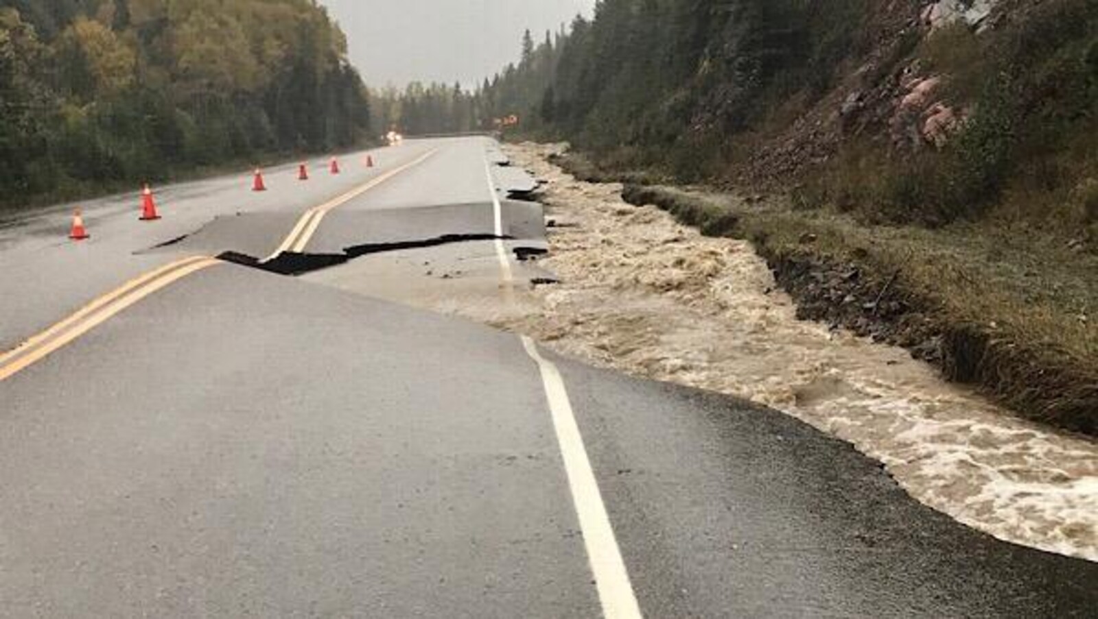 Une route affaissée avec beaucoup d'eau en bordure.
