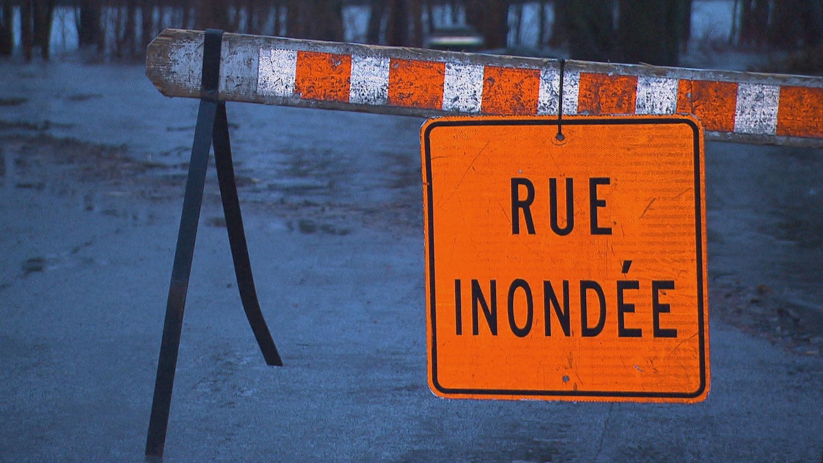 Une pancarte orange avec l'inscription « rue inondée »