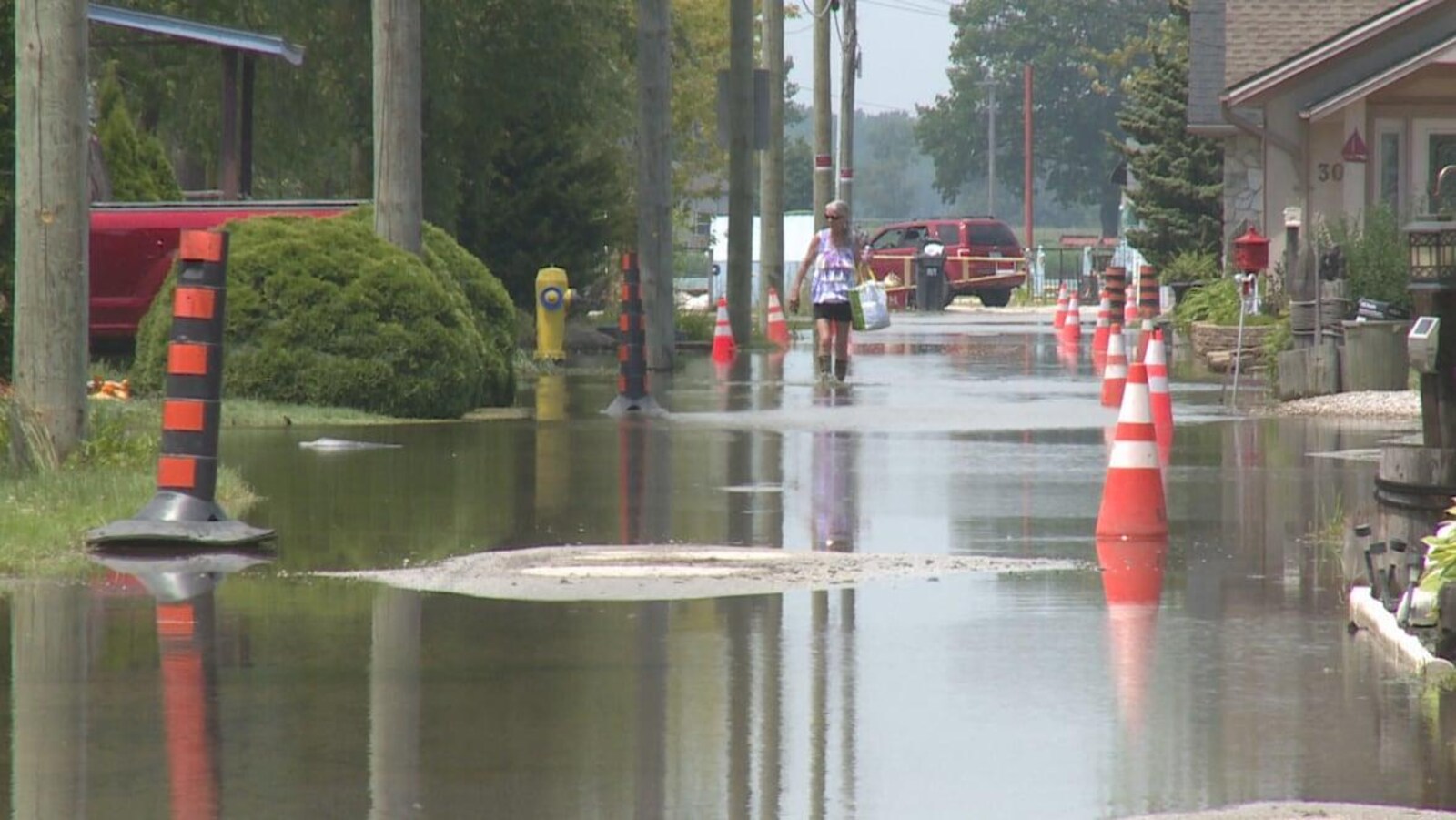 Une femme marche en botte de pluie dans une rue inondée