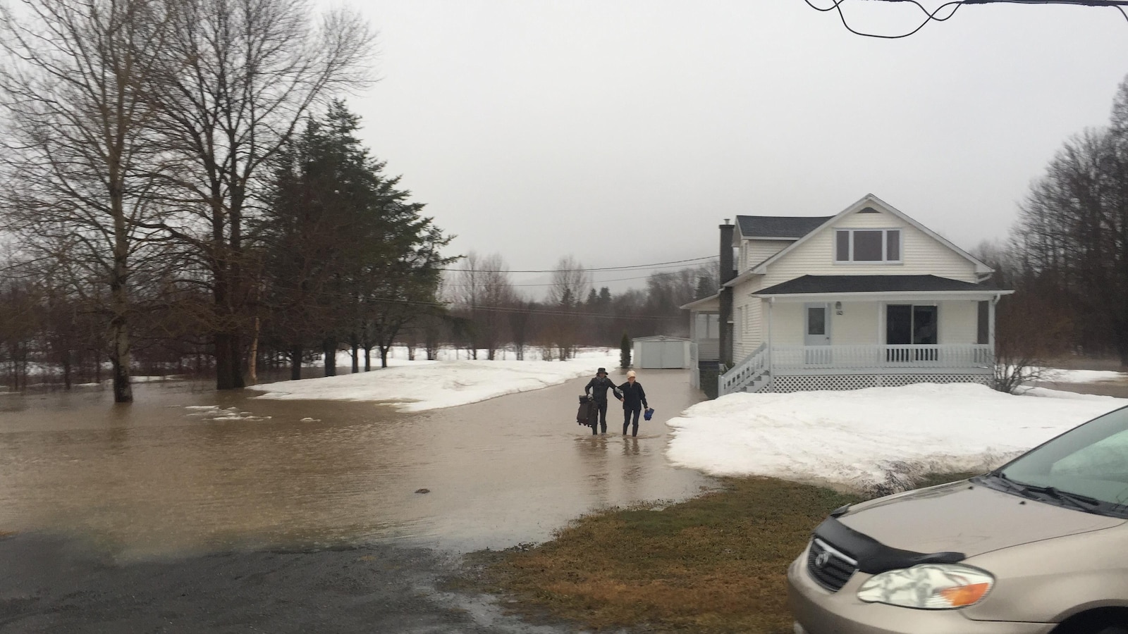 Deux personnes traînent des bagages sur un chemin inondé.