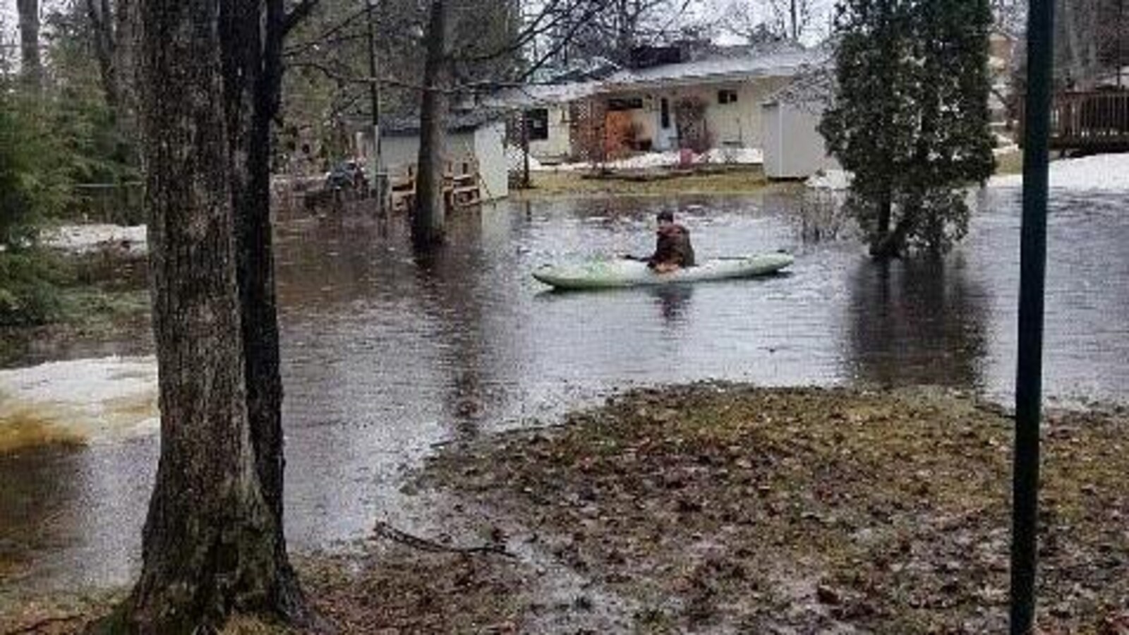 Un résident de North Bay en kayak devant sa maison entourée d'eau.