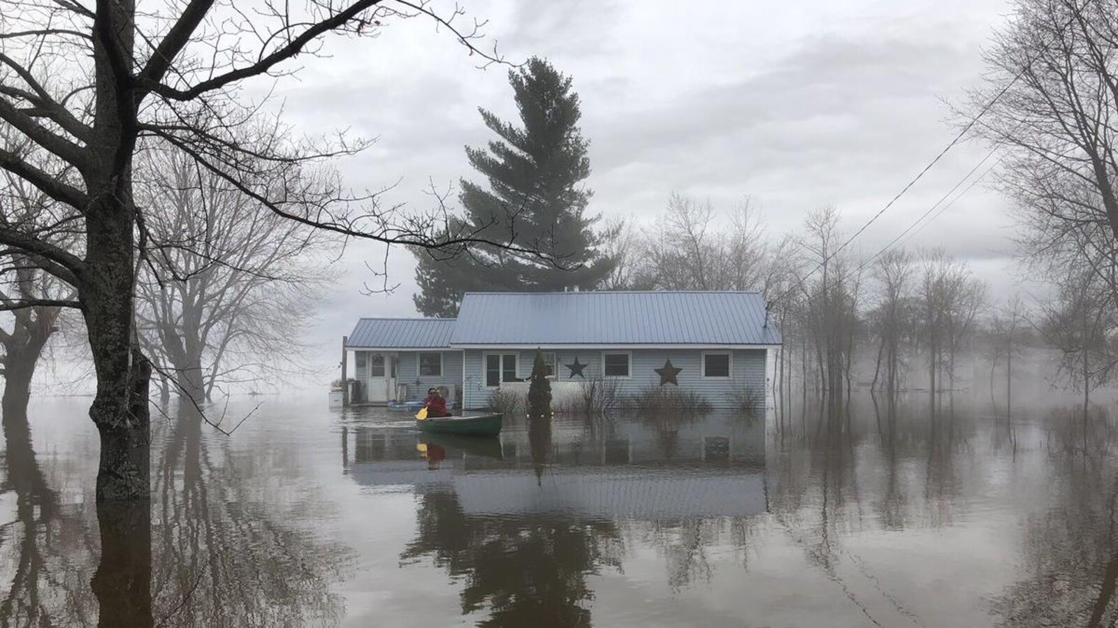 Une personne quitte sa maison en canot.