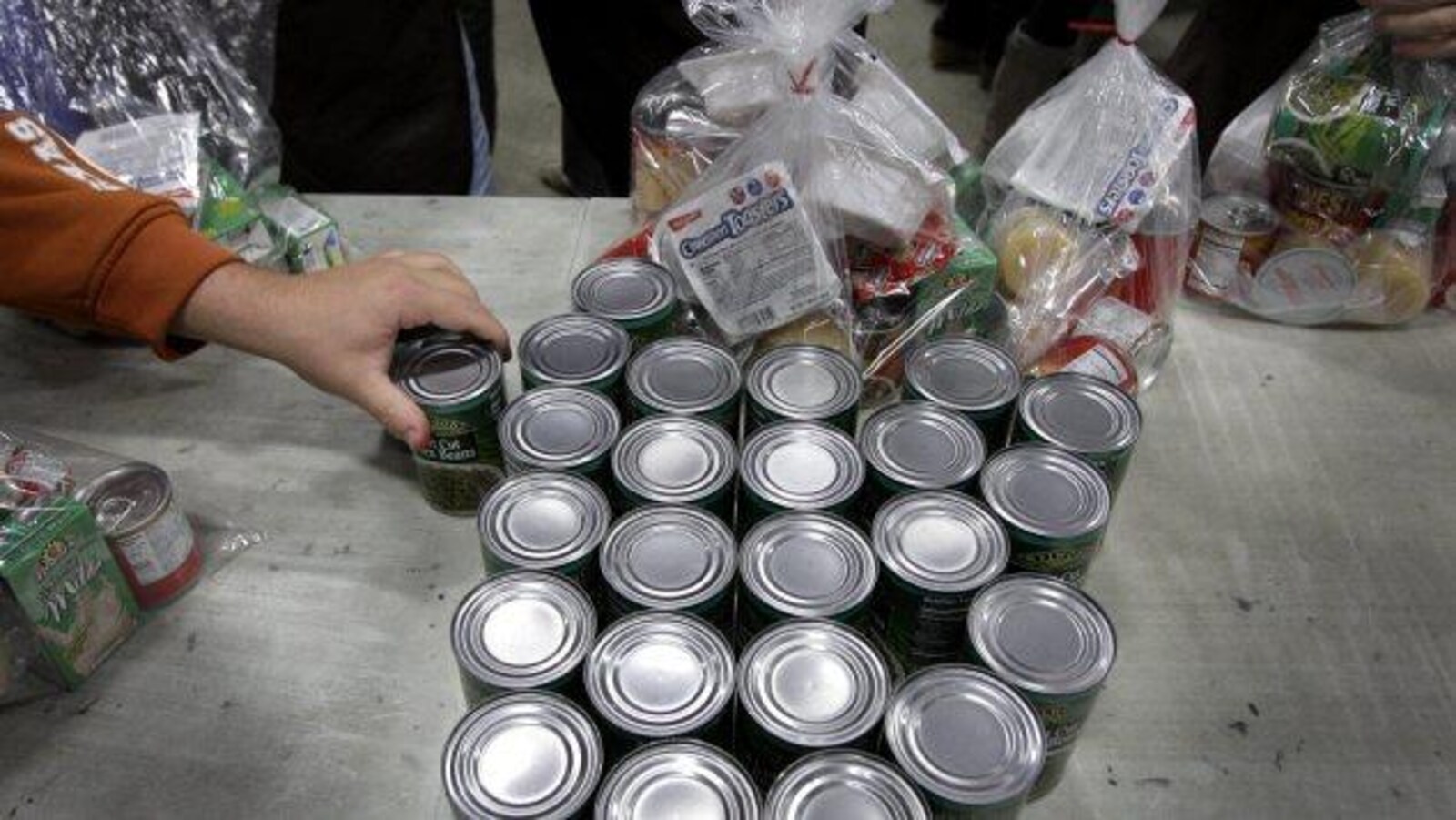Boîtes de conserve dans une banque alimentaire, une main se sert une boîte