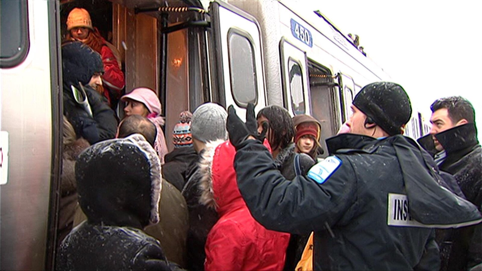 Des usagers font la file pour pénétrer dans un train de banlieue sous la supervision d'un inspecteur.