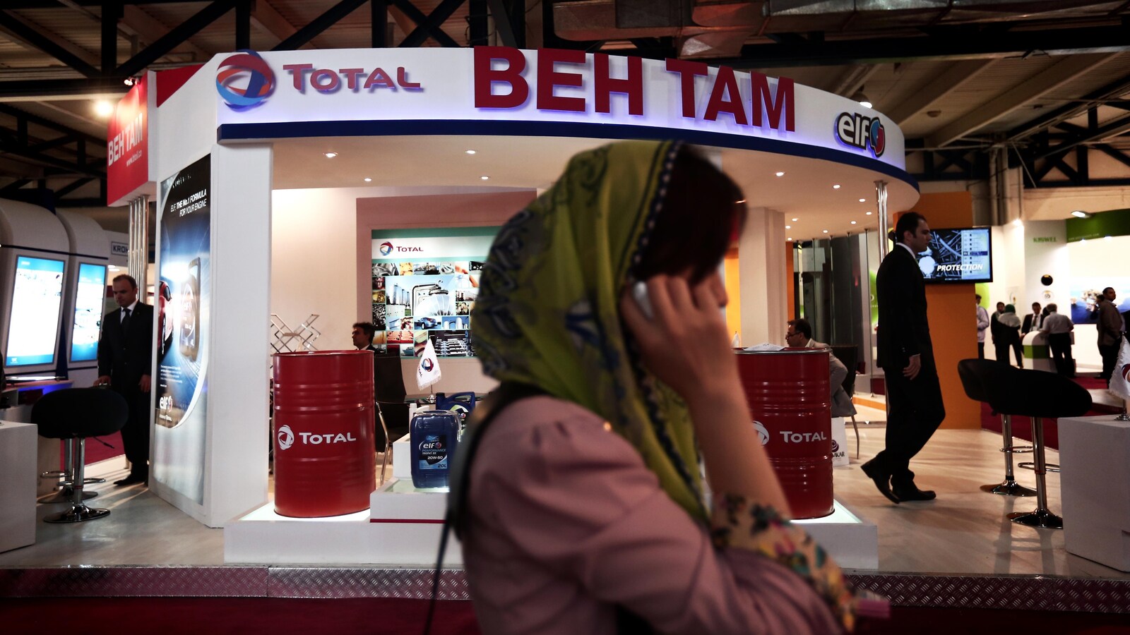 Une femme parle au téléphone en passant devant un kiosque de la pétrolière Total.