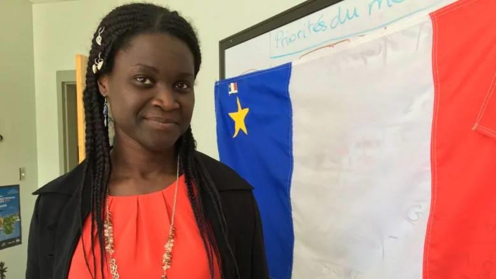 Isabelle Dasylva-Gill devant un drapeau acadien.