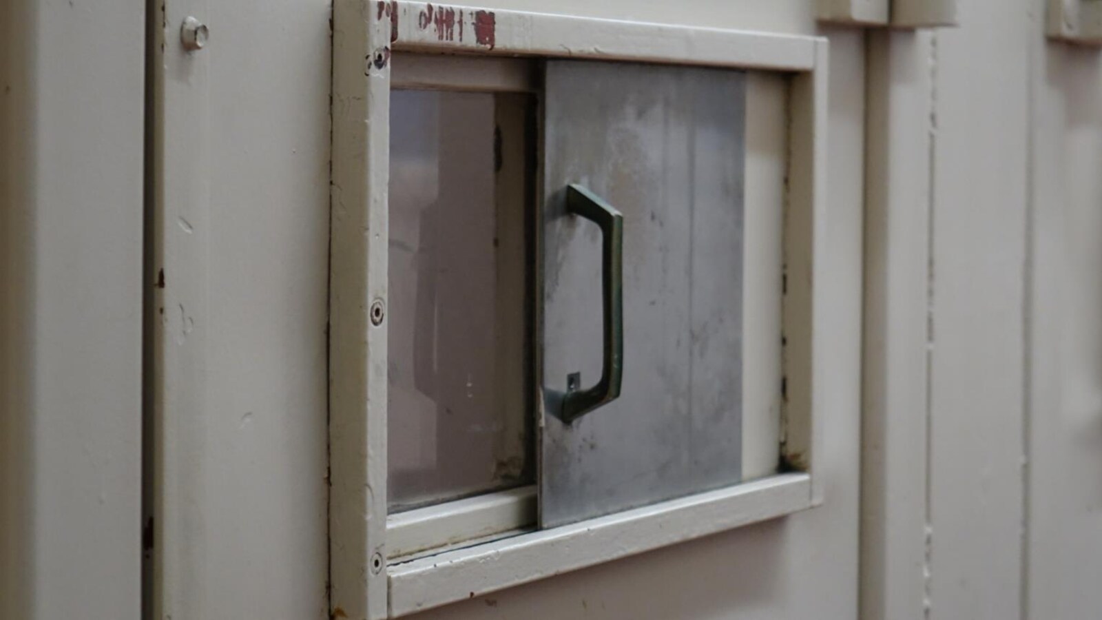 Photo d'une petite fenêtre dans une porte de prison.