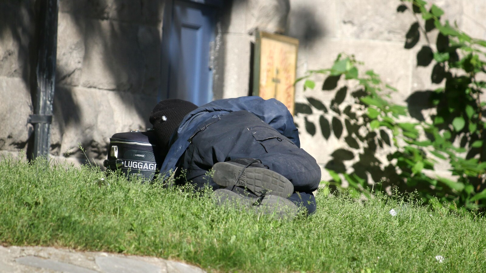 Une personne en situation d'itinérance dort sur un terrain au centre-ville de Montréal.