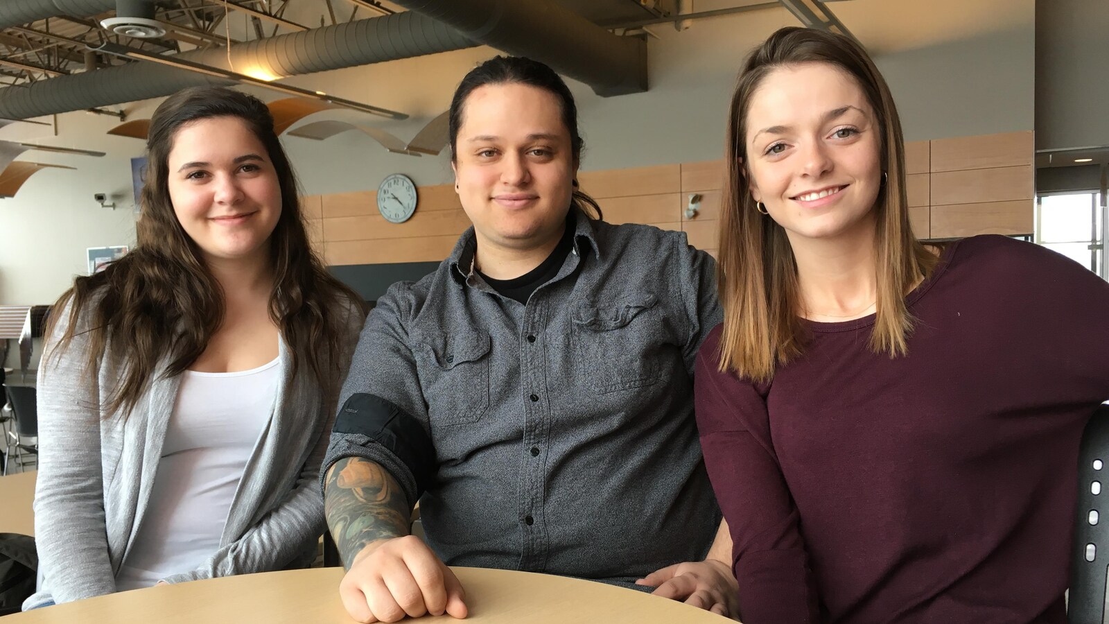 Trois étudiants sourient à la caméra.