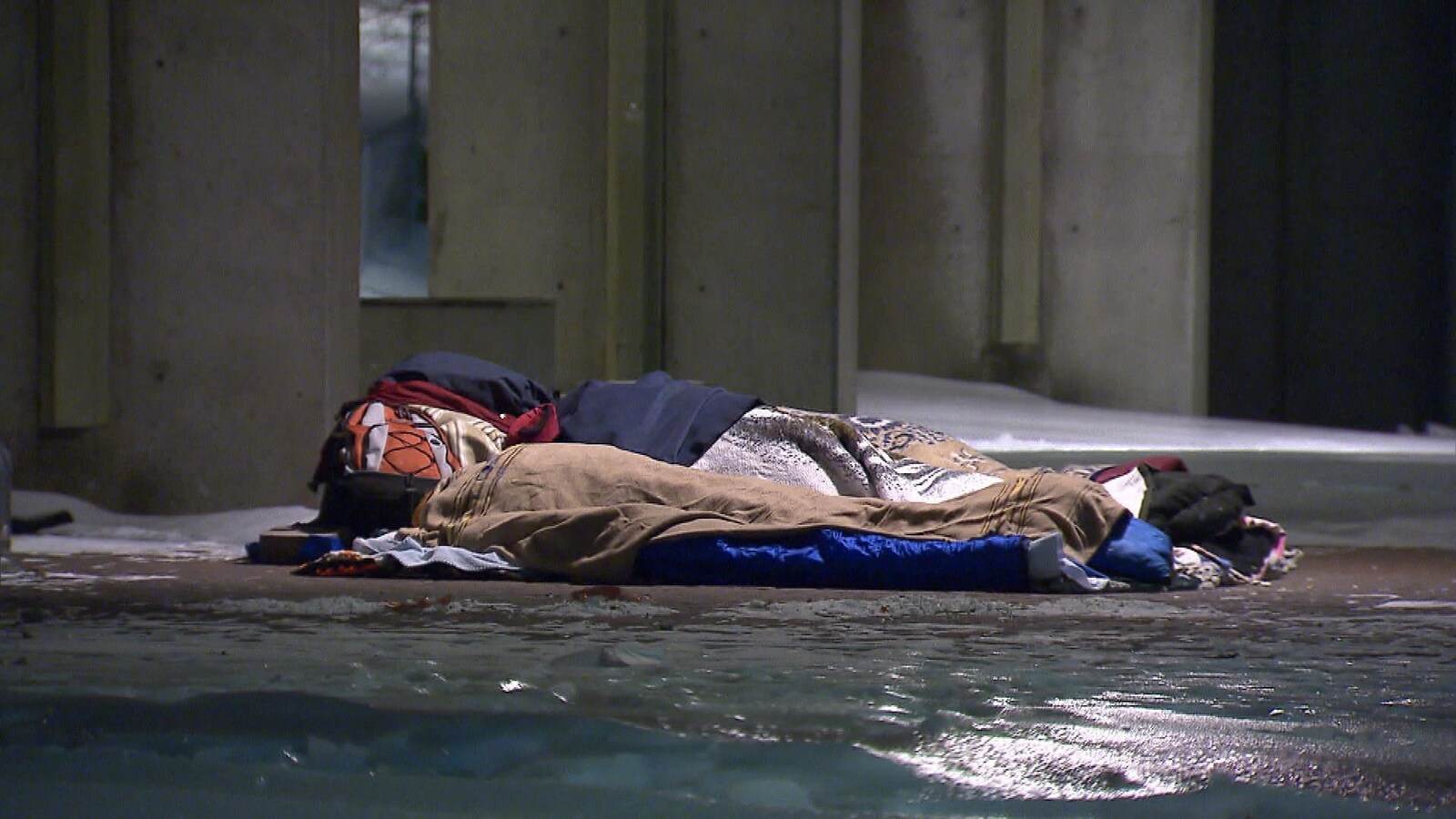 Un sans-abri dormant sur le sol, en plein hiver.