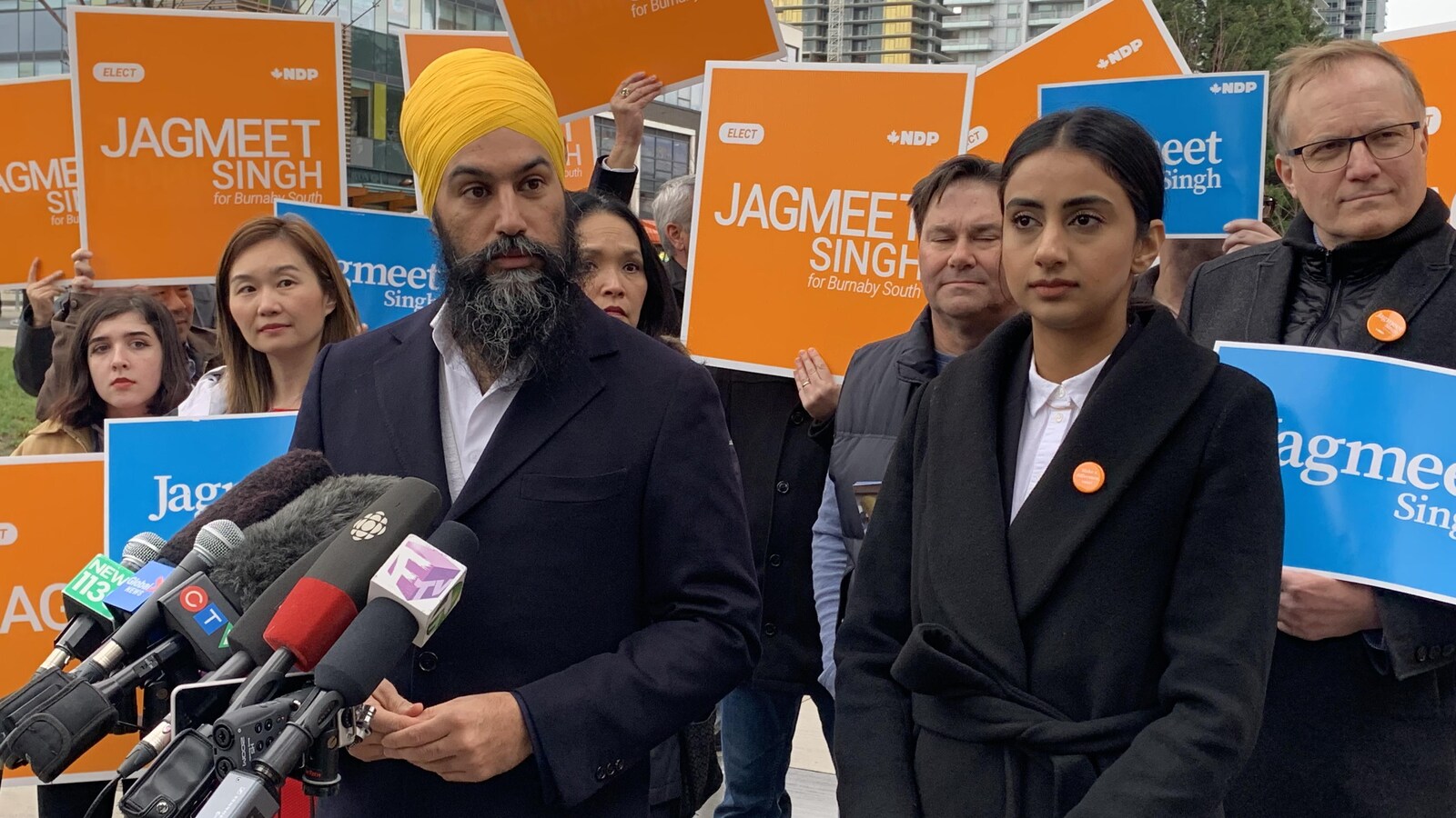 Jagmeet Singh et son épouse Gurkiran se tiennent aux côtés de miliants néo-démocrates qui tiennent des affiches au nom de leur candidat.