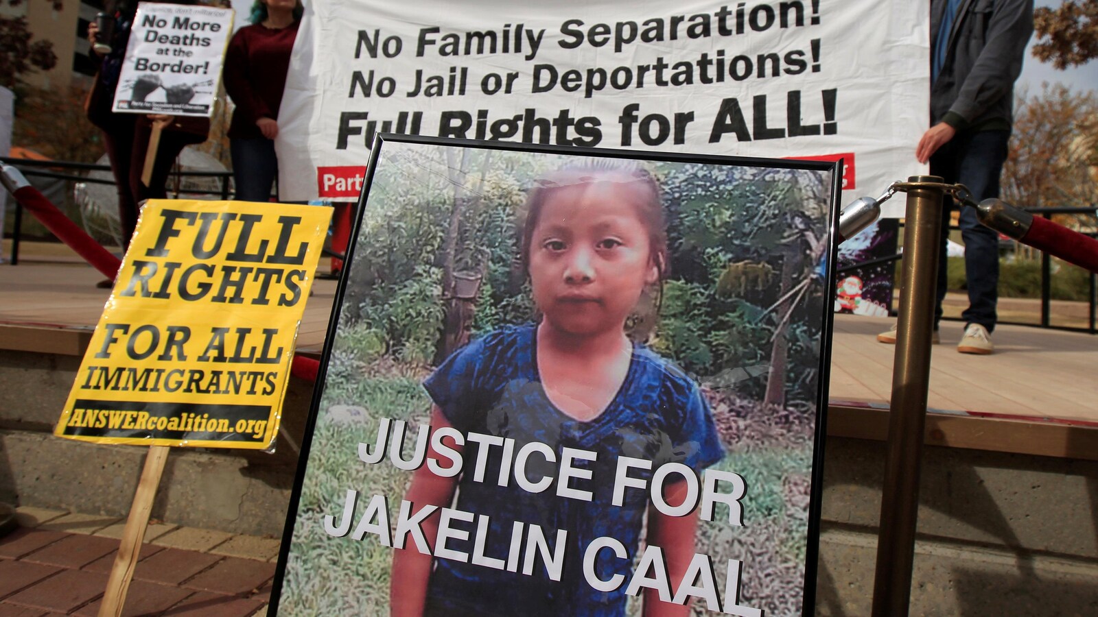 Des gens tiennent des banderoles et des affiches où figurent la photo de Jakelin Caal et des messages demandant justice pour la fillette de 7 ans.