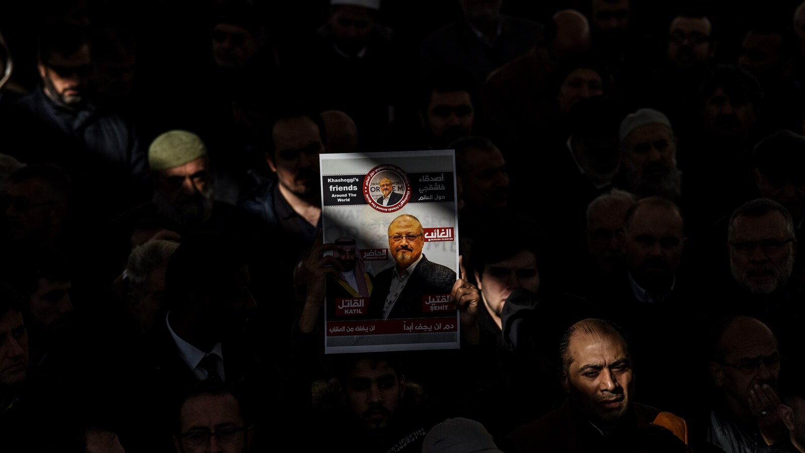 Au beau milieu d'une foule, un homme tient bien en évidence une affiche sur laquelle on voit une photo de Jamal Khashoggi.