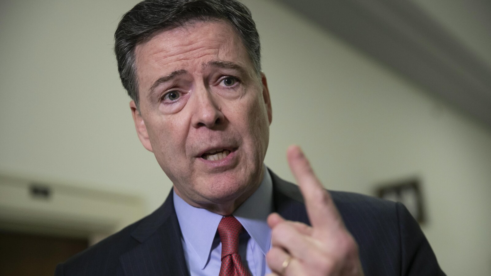 James Comey, l'index levé, s'adresse aux journalistes.