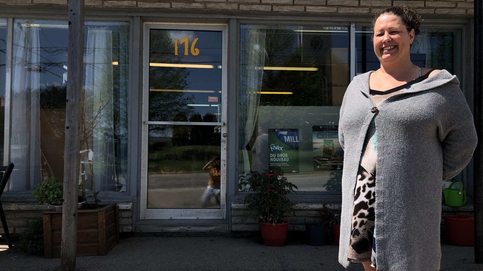 Une femme sourit devant son commerce.