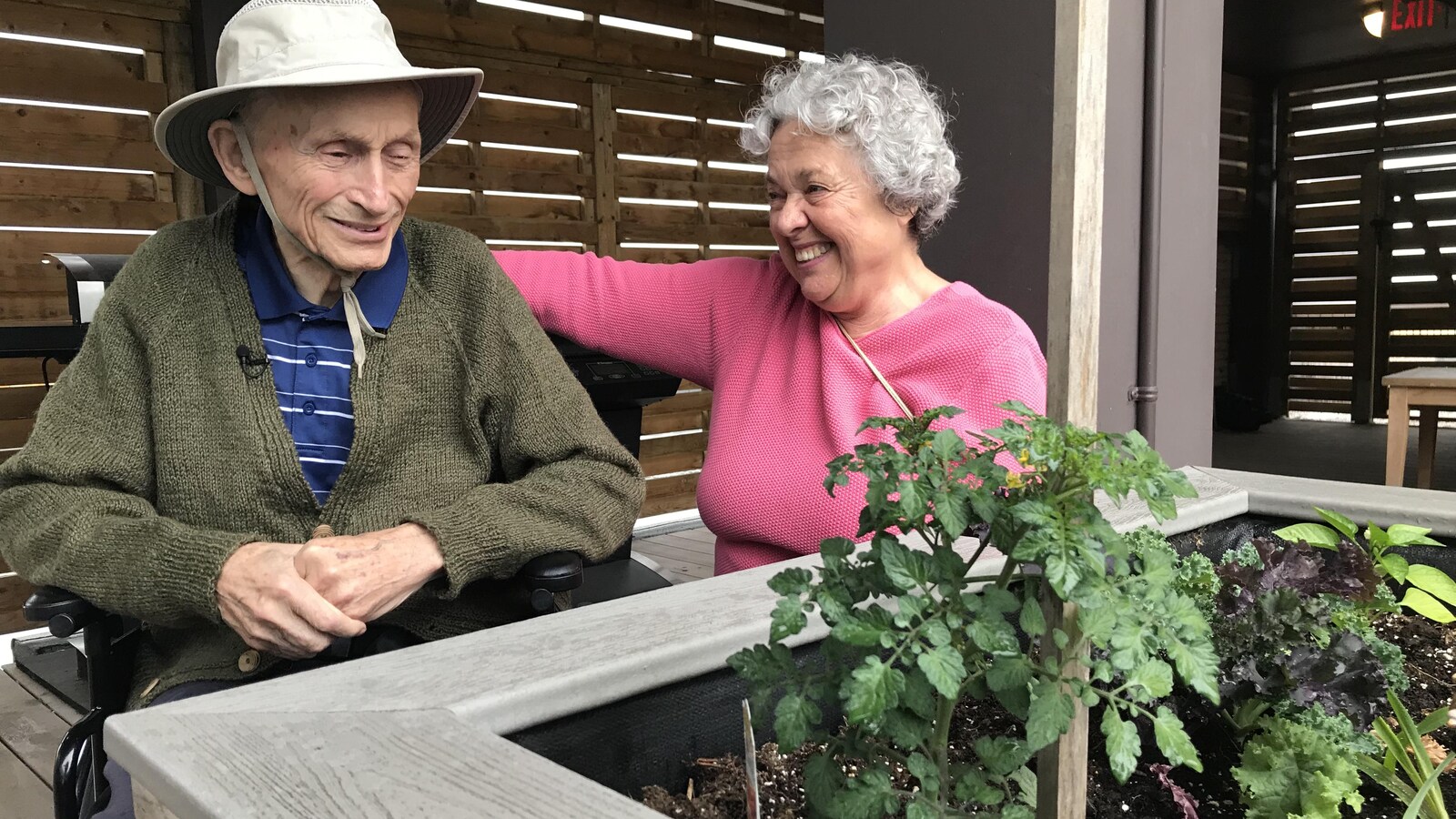 Un couple de personnes âgées devant un potager.