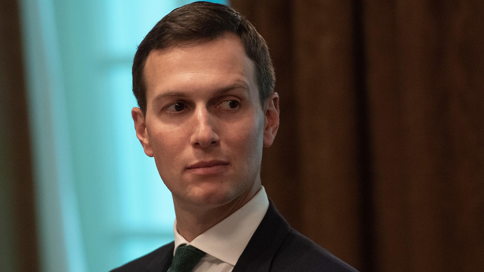 Un jeune homme aux cheveux impeccablement peignés regarde de biais.