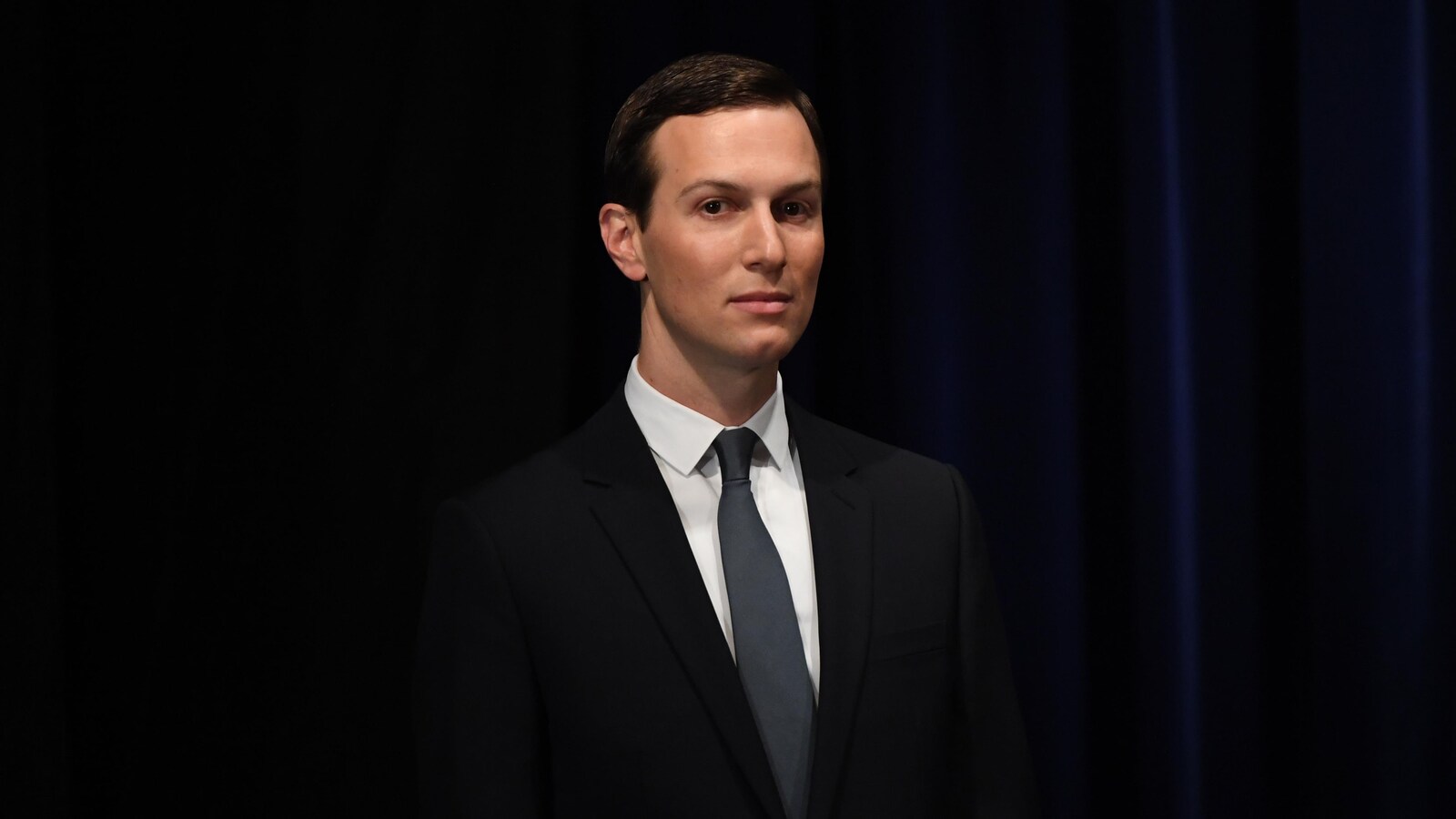 Jared Kushner pose devant un rideau pour la caméra.