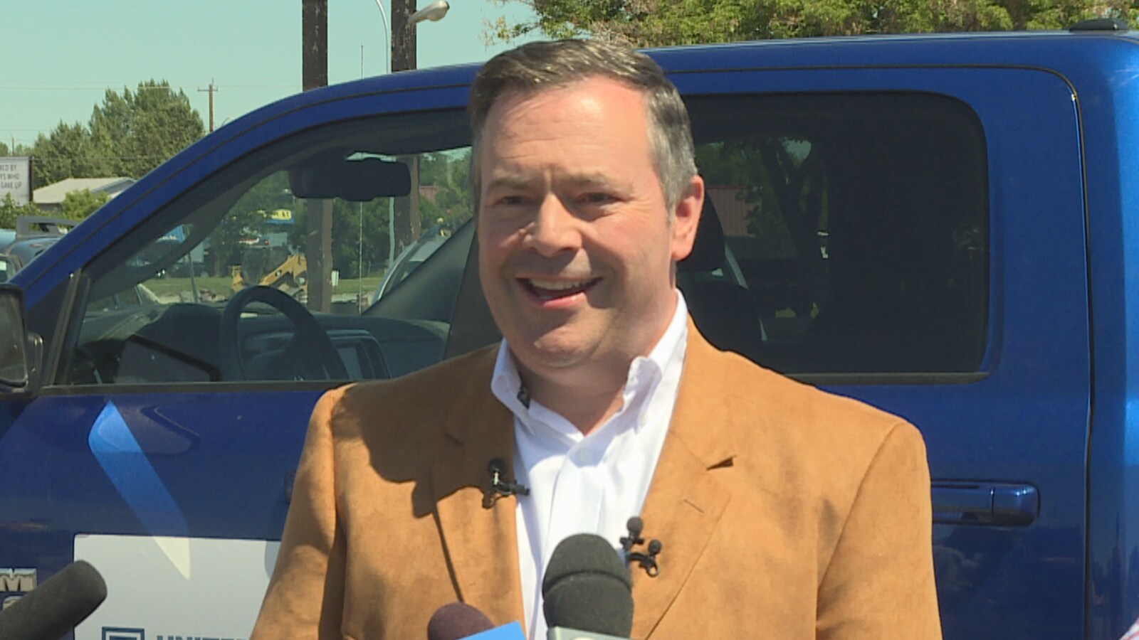Une photo de Jason Kenney entouré de micros.