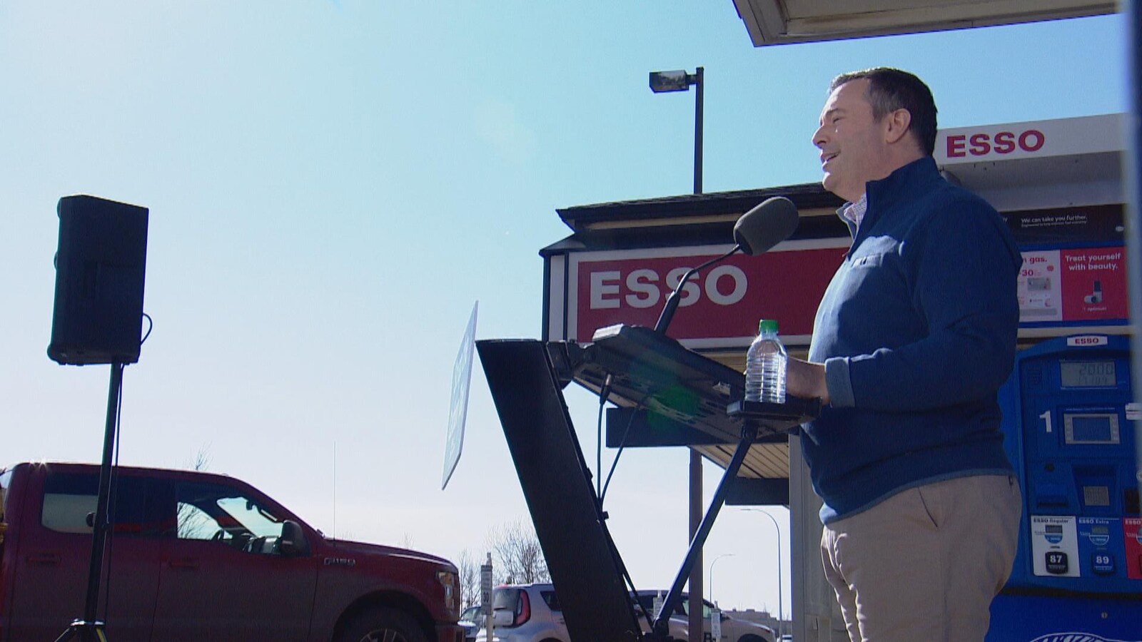 Jason Kenney de profil. Derrière, il y a le logo de la station-service Esso.