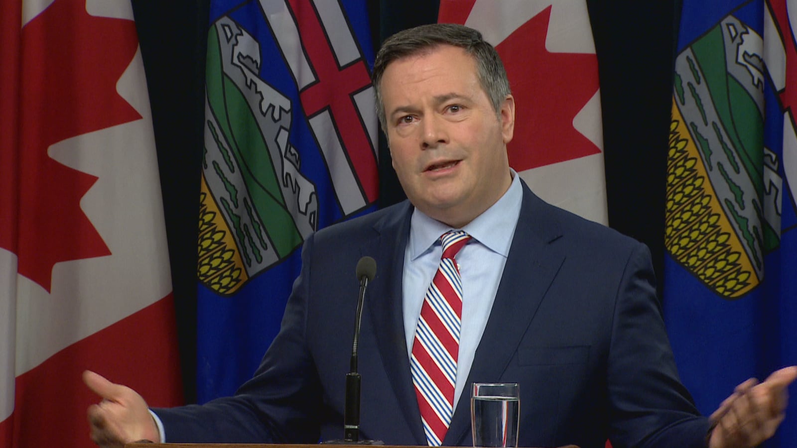 Jason Kenney parle devant des drapeaux albertains et canadiens.