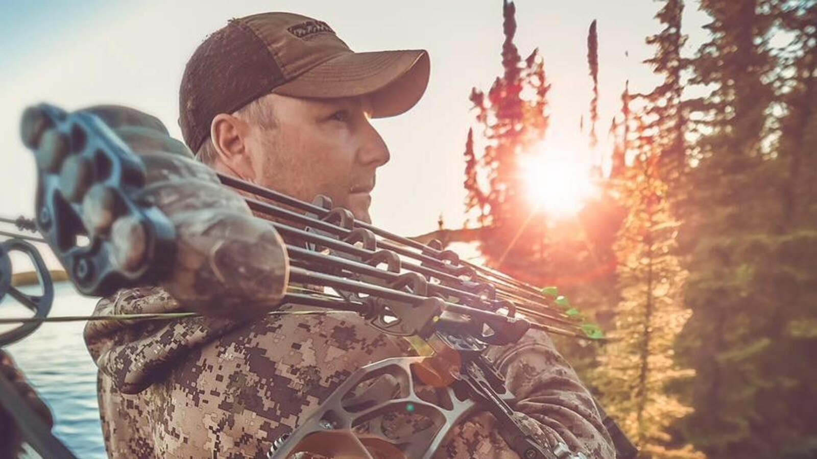Le chasseur Jason Peterson en tenue de chasse et portant une casquette au bord d'un plan d'eau