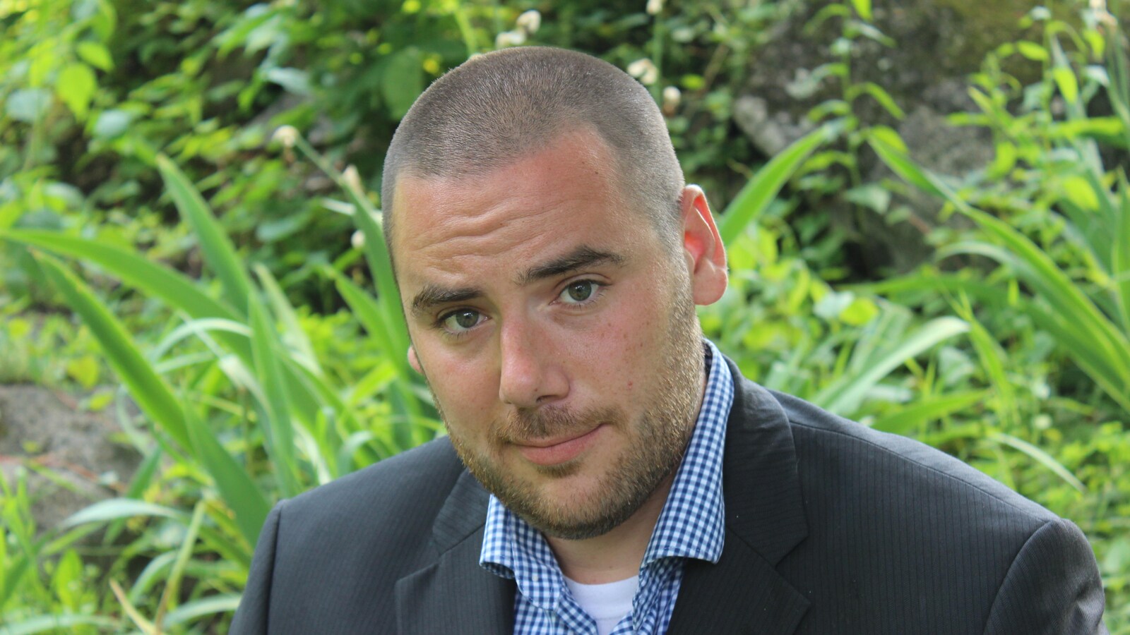 Le candidat du Parti vert du Québec, Jasper Boychuk, à l'extérieur, devant des plantes.